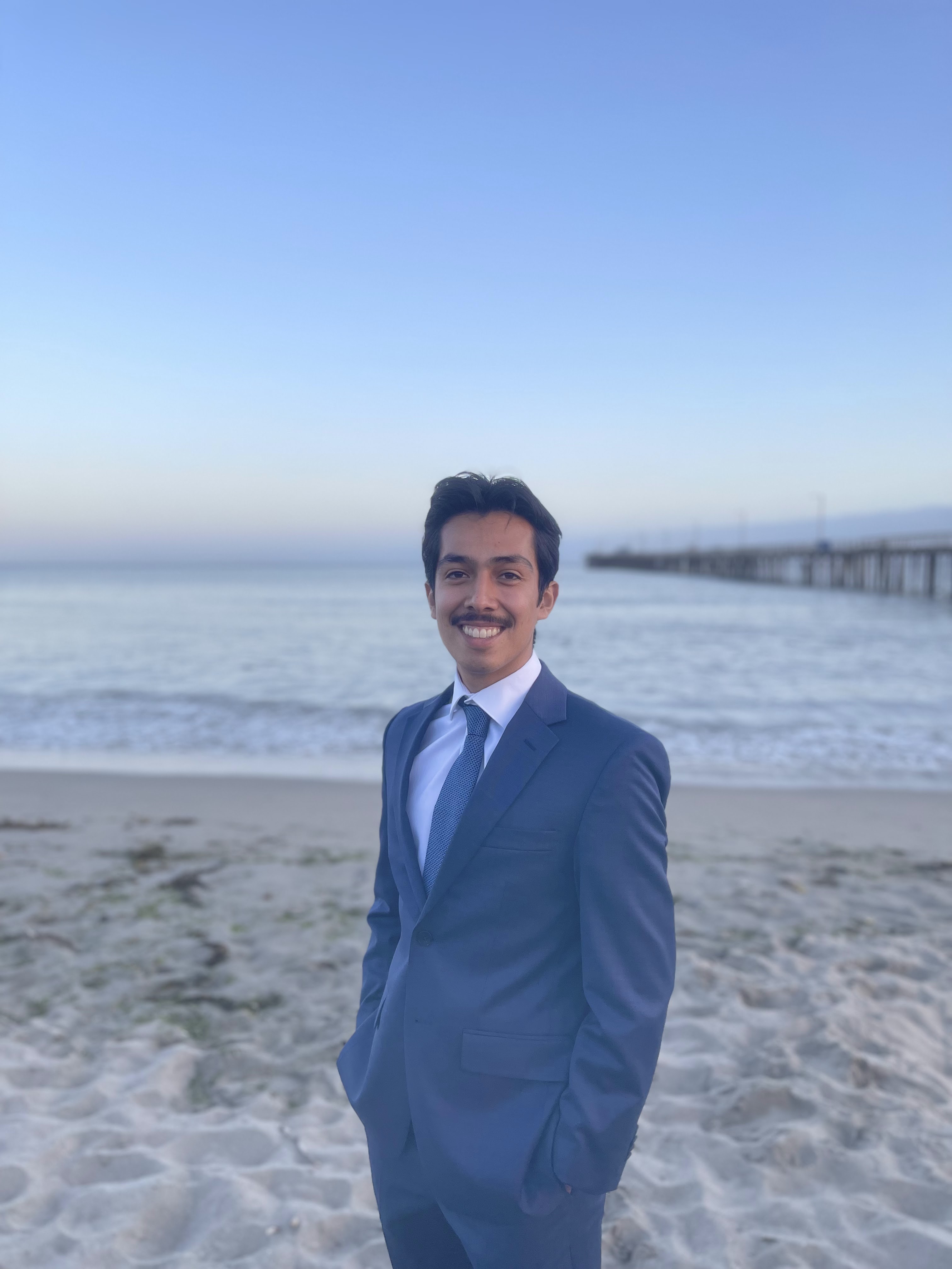 A profile picture of me on the beach shore. There is a pier in the background.